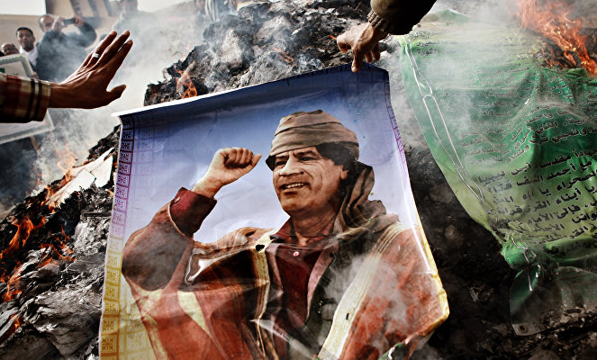 Жители Бенгази сжигают портреты Муамара Каддафи, плакаты с его цитатами и "Зеленую книгу" Каддафи.