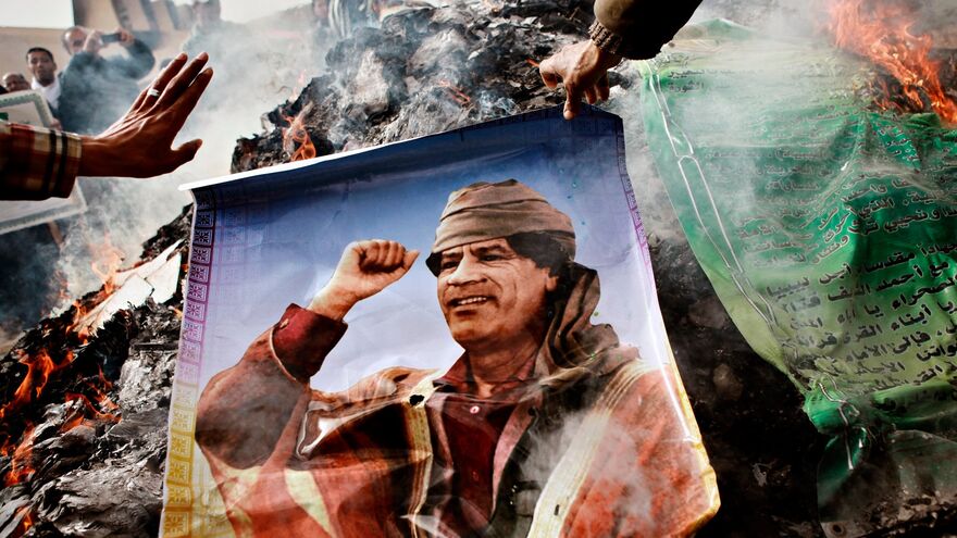 Жители Бенгази сжигают портреты Муамара Каддафи, плакаты с его цитатами и Зеленую книгу Каддафи.