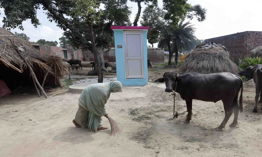 Женщина подметает улицу перед новым туалетом в деревне Катра, округ Бадаун.